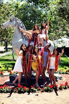 a group of young women standing next to each other in front of a horse statue