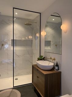 a white sink sitting under a bathroom mirror next to a walk in shower and toilet