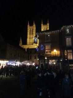 a crowd of people standing around in front of a building with christmas lights on it