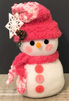 a stuffed snowman wearing a pink hat and scarf