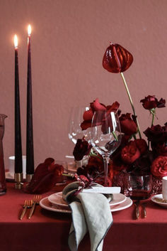 the table is set with red flowers and candles