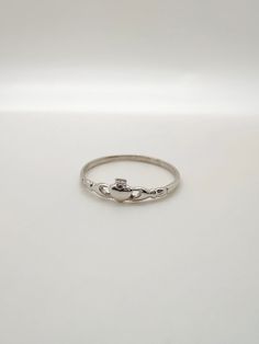 a silver ring with two small beads on the inside of it, sitting on a white surface