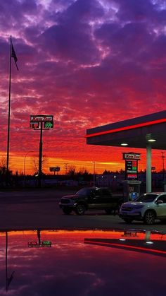 cars are parked in front of a gas station at sunset