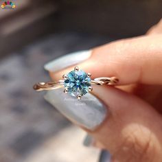 a woman's hand holding an engagement ring with a blue topazte stone