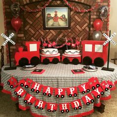 a birthday party with red and black decorations, train cake table cloths and balloons