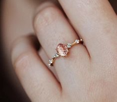 a woman's hand with a pink diamond ring on it