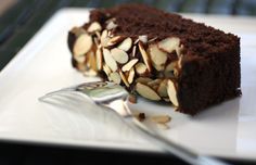 a piece of chocolate cake with almonds on top and a fork next to it