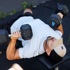 a man laying on top of a bench holding two dumbbells in his hands