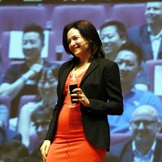 a woman standing in front of a projection screen holding a cell phone to her ear