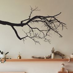 a tree branch with no leaves is shown on the wall above a fireplace mantel