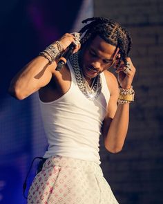 a young man with dreadlocks on his head and wearing a white tank top