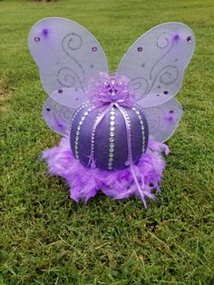 a purple and white fairy ball sitting in the grass