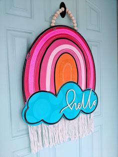 a door hanger with the word hello written on it and a rainbow in the background