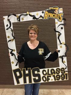 a woman standing in front of a brick wall holding up a phs class sign