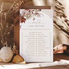 a white card with flowers on it sitting next to a vase filled with dried plants