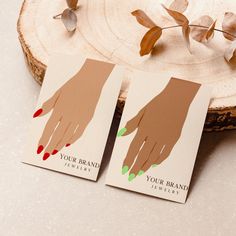 two business cards with hands on them sitting next to a piece of wood and some leaves