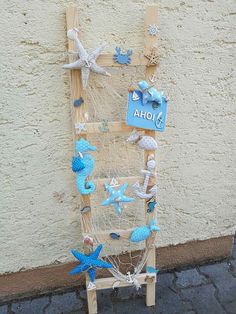 a wooden ladder with sea shells and starfishs attached to it, next to a wall