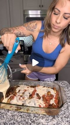 a woman in a blue tank top is making some kind of dish on the counter