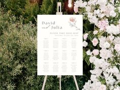 a wedding seating sign with flowers in the background