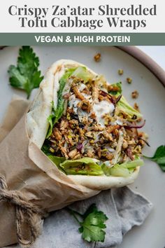 a wrap filled with meat and vegetables on top of a white plate next to a napkin