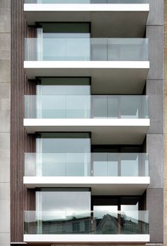 an apartment building with balconies and glass windows on the side of each floor