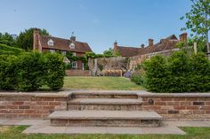 a large brick house sitting on top of a lush green field