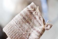 a person holding up a piece of fabric with a pin in it's middle