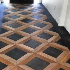 the floor is made out of wood and has black tiles on it, along with white walls