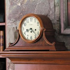 a clock sitting on top of a wooden mantle