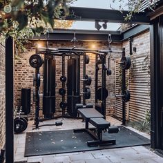 a home gym with lots of equipment in the back yard and brick wall behind it