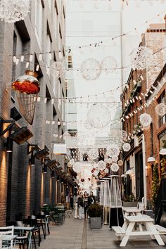 an empty city street with lights strung from the ceiling and tables in front of it