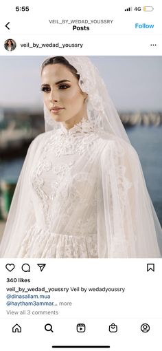 a woman wearing a wedding dress and veil on her head, standing in front of the ocean