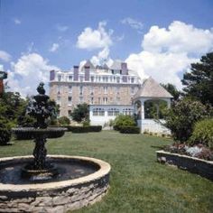 a large building with a fountain in front of it and trees around the yard area