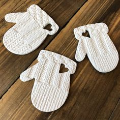 three white knitted mittens and gloves on a wooden surface