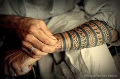 an old man with a tattoo on his arm holding onto another person's hand