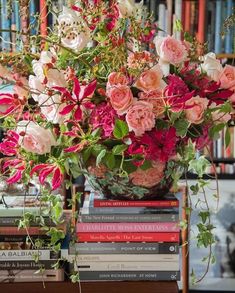 a vase filled with pink and white flowers sitting on top of a table next to books