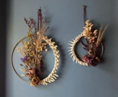 two wreaths with dried flowers are hanging on the wall