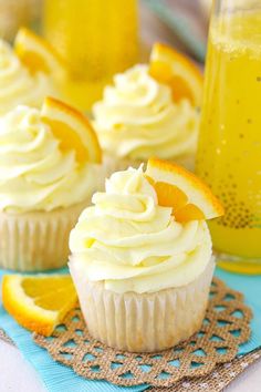 cupcakes with frosting and orange slices on a doily next to a drink