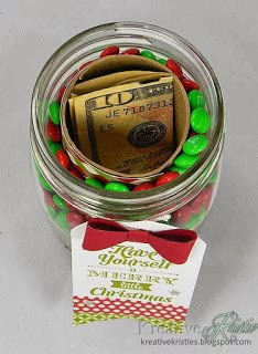 a jar filled with candy and money sitting on top of a white table next to a tag