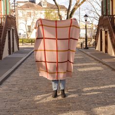 a person walking down a brick road holding a blanket