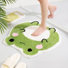 a person standing on top of a green and white rug next to two slippers