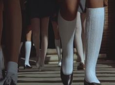 there are many people walking down the street wearing white socks and knee high socks with black heels