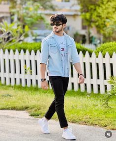 a man walking down the street with his hand in his pocket and wearing white sneakers