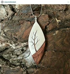 a wooden pendant with a tree on it hanging from a rock wall in front of a stone background