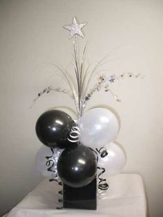 black and white balloons in a vase with star decoration on the top, sitting on a table