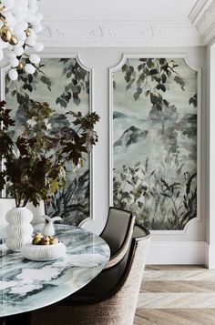 a dining room table with chairs and paintings on the wall behind it in an elegant style