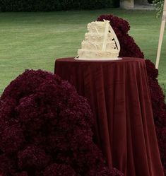 a wedding cake sitting on top of a table covered in purple flowers next to an umbrella