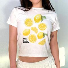 Add a pop of summer to your wardrobe with our Lemons Graphic Baby Tee! This 90s-inspired design features a fun and playful aesthetic, perfect for any fashion-forward individual. Made with high-quality materials, our easy peasy lemon squeezy baby tee is both trendy and comfortable. A must-have addition to your Y2K colle Lemon Graphic, Lemon Shirt, Easy Peasy Lemon Squeezy, Playful Aesthetic, Graphic Baby Tee, Baby Graphic Tees, Lemon Meringue, 90s Inspired, Unique Gifts For Her