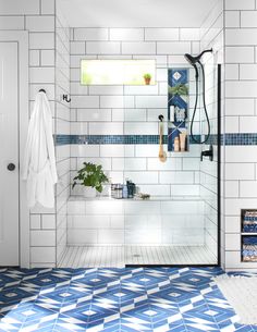 a bathroom with blue and white tiles on the floor, shower head, and bathtub