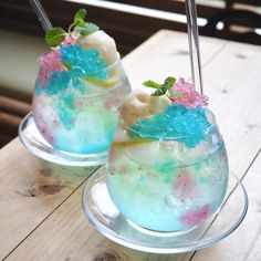 two glasses filled with ice cream and sprinkles on top of a wooden table